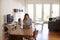 Woman Working From Home Using Laptop On Dining Table