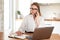 Woman working on laptop at home on kitchen. talking on phone. Blonde woman business. Woman trying to find a job