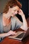 Woman working on laptop leaning on desk