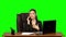 Woman working on a laptop then answers the call by mobile phonen, suprised and very upset . Green screen