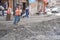 A woman is working on an ongoing construction works going at an Indian Street. Construction machine has dug up a trench in a road