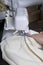 The woman is working on the product on the overlock. Overlock with white thread. The woman directs the cloth clamped in the claw o