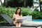 A woman working at the swimming pool with her laptop computer holding paperwork in her hand. It is imperative for young Asian