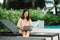 A woman working at the swimming pool with her laptop computer holding paperwork in her hand. It is imperative for young Asian