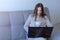 Woman working typing on laptop at home sitting on couch, freelance distant work.