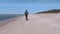 Woman with workout mat walking near sea in windy day