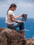 Woman works on her laptop on the cliffs