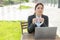 A woman works remotely in the open air and puts on a medical mask. A female employee in a suit is typing on a laptop on