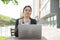 A woman works remotely in the open air and puts on a medical mask. A female employee in a suit is typing on a laptop on