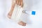 Woman is wrapping her leg with sprained ankle with elastic bandage  on white background. Twisted bandaged ankle and gel on