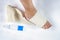 Woman is wrapping her leg with sprained ankle with elastic bandage  on white background. Twisted bandaged ankle and gel on