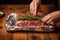 Woman wrapping meat with rosemary in aluminum foil. Generate Ai