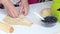 A woman wraps blueberries in a dough that are lying on a rolled dough. Cooking dumplings