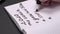 A woman writes a list of goals for 2020. Notebook on a dark table. Close up of a female hand