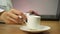 Woman writes notes while drinking coffee from a white cup. Work at laptop and drink a cup of coffee.