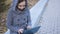 Woman writing on laptop on park bench