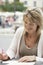 Woman Writing Letter At Outdoors Cafe