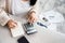 Woman writing a list of debt on notebook calculating her expenses with calculator with many invoices , female hand doing