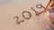 Woman writting 2019 on sand beach. ocean wave and lettering on the beach. Happy New Year 2020. Vacation 2019 2020