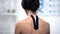Woman with Y-shaped tape on upper back, reducing pain, alternative medicine