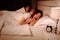 Woman yawning in bed while her husband using mobile phone next t