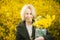 Woman on a yellow background with yellow flowers. Smiling middle aged blonde woman forty plus. Happy face, light thoughts, dreams