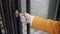 Woman in a yellow coat opens the door of a cafe with a key.