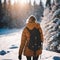 woman in yellow coat walking on snowy trail with backpack and snowboards