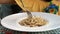 Woman in a yellow dress is eating a pasta with white sauce.