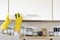 Woman in yellow gloves washes the door in kitchen cabinet