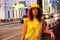 Woman in a yellow hat and clothes against the background of the evening lights of the big city, passing car in the