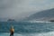 Woman with yellow jacket looking the fierce ocean