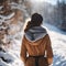 woman in yellow jacket standing in snow near tree lined hill