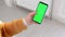 A woman in a yellow knitted sweater with a smartphone and a green phone screen swipes her finger across the screen. The