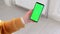 A woman in a yellow knitted sweater with a smartphone and a green phone screen swipes her finger across the screen. The