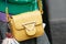 Woman with yellow leather Sara Battaglia bag and green jacket before Fendi fashion show, Milan Fashion Week