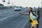 Woman in yellow overalls hitchhiking and holding map