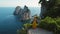 Woman in yellow overlooking the stunning seascape of Capri Island from a cliffside. Iconic Faraglioni sea stacks