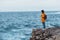 woman in yellow raincoat at the cliff enjoying sea view at stormy weather