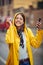 Woman in a yellow raincoat listens to music in the rain