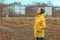 Woman in yellow raincoat looking up at rainy clouds