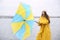 Woman in yellow raincoat with umbrella caught in gust of wind near river