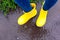 Woman in yellow rubber boots standing in the puddle in rain