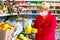 A woman in yellow rubber gloves chooses a citrus fruit in a store. Protection from coronavirus