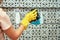 Woman in yellow rubber gloves cleans glass bathroom shower cabine
