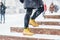 A woman in Yellow shoes rises on steps in sity