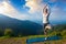 Woman in yoga asana Vrikshasana tree pose in mountains outdoors