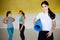 Woman with yoga mat posing with friends in gym