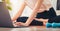 Woman on a yoga mat and watch exercise online via the laptop on the bedroom