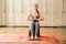 Woman in yoga studio sitting with feet on Sadhu board with sharp metal nails. Yoga and health concept